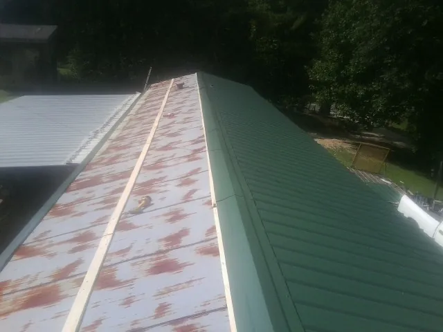 Old rusted panels beside newly installed green metal roofing — Wind Damage Roof Repair by Roofing Brothers in Alamo