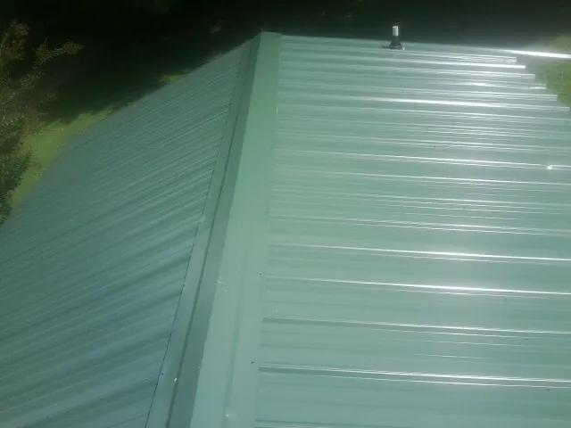 New green metal panels meeting at the ridge of a roof in Alamo
